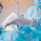 Ein medizinischer fachmann trägt ein paar weiße puderfreie hygienster latexhandschuhe med grip im operationssaal