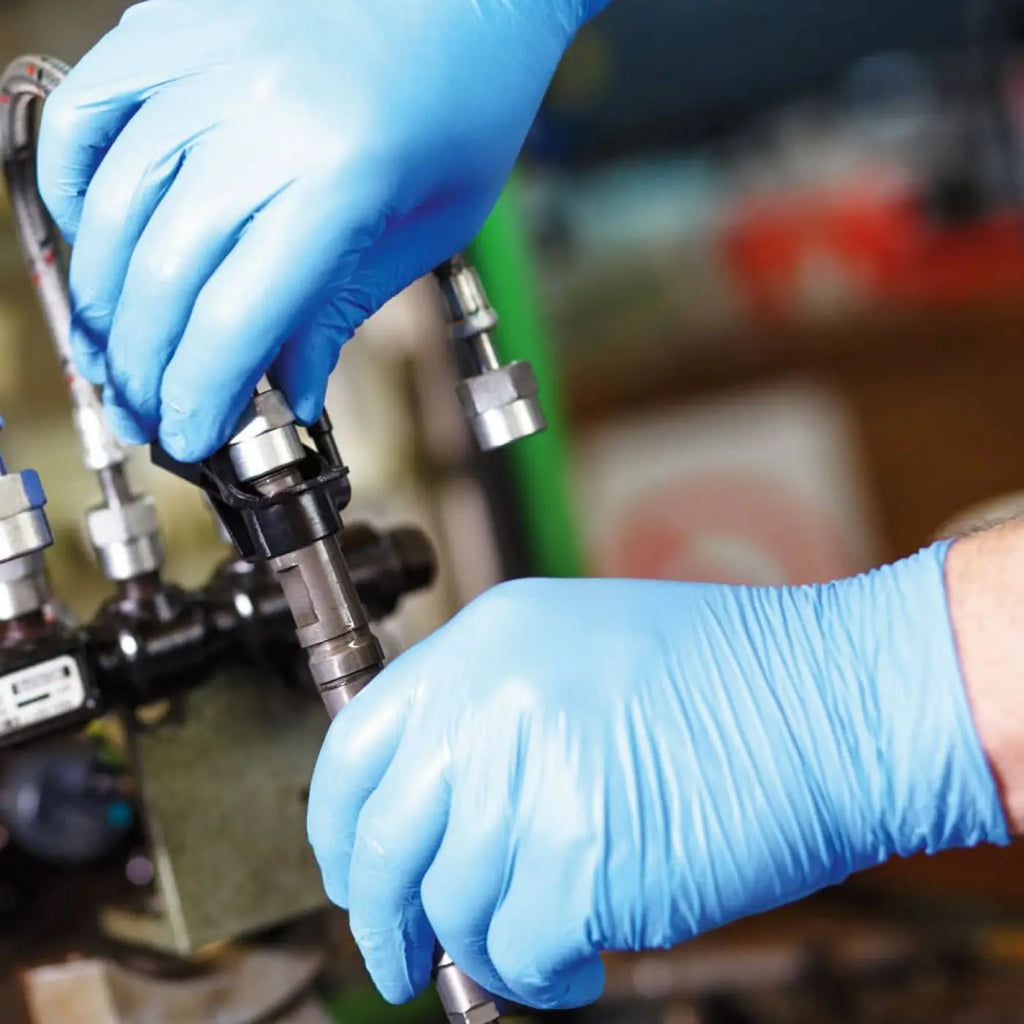Blaue nitril handschuhe von hygostar safe premium greifen metallischen kraftstoffeinspritzdüsen mit schwarzen plastikteilen