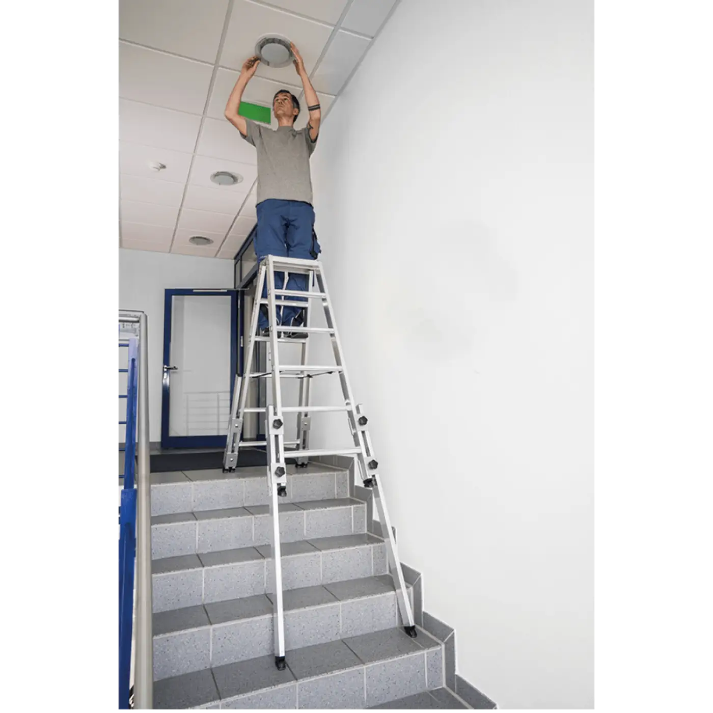 Person auf aluminiumleiter hält silberne runde deckenleuchte mit stehleiter münk treppengängig