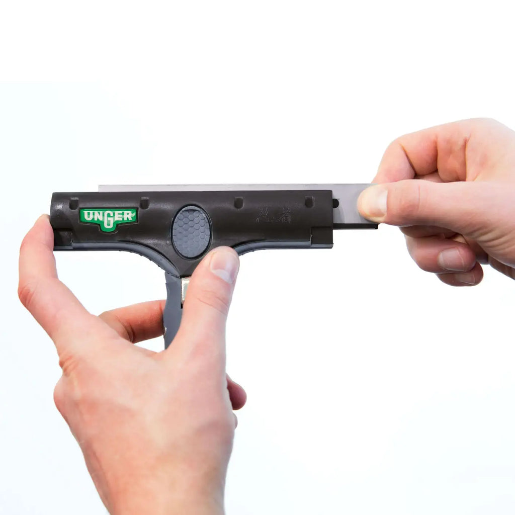 Schwarzes unger ergotec ninja 6in1 fensterreinigungswerkzeug mit silberner metallklinge wird in griff eingesetzt