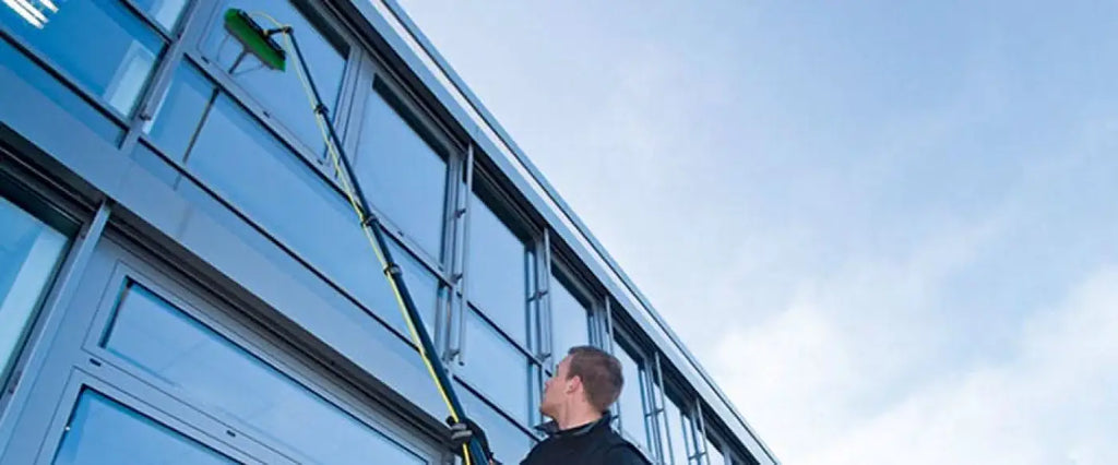 Ein mann verwendet die grüne und schwarze ungere nlite connect ultra himod karbon erweiterungsstange zum reinigen von fenstern